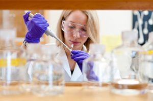 Woman with pipette in lab working on drug development process